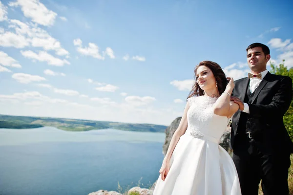 Hochzeitspaar in atemberaubender Landschaft mit Fels und See. — Stockfoto
