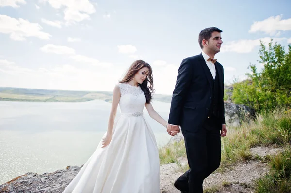 Wedding couple at breathtaking landscape with rock and lake. — Stock Photo, Image