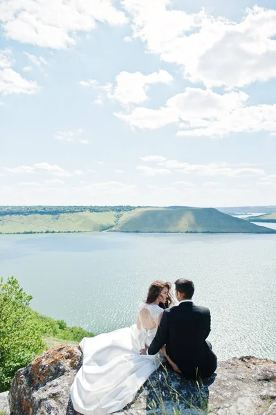 Hochzeitspaar in atemberaubender Landschaft mit Fels und See. — Stockfoto