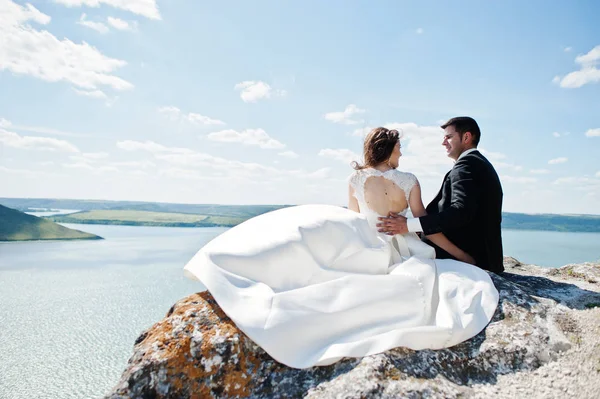 Pareja de bodas en un paisaje impresionante con roca y lago . — Foto de Stock