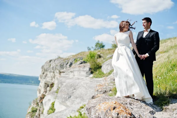 Bröllopsparet på hisnande landskap med rock och sjö. — Stockfoto