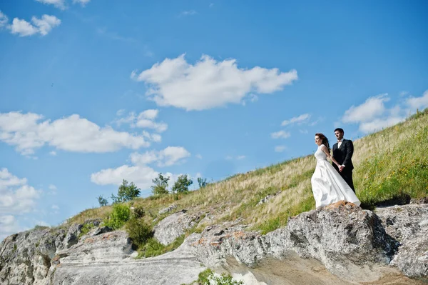 Bröllopsparet på hisnande landskap med rock och sjö. — Stockfoto