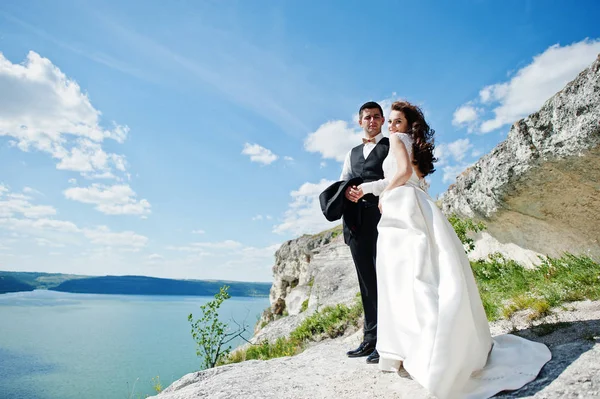 Pareja de bodas en un paisaje impresionante con roca y lago . — Foto de Stock