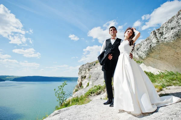 Pareja de bodas en un paisaje impresionante con roca y lago . — Foto de Stock