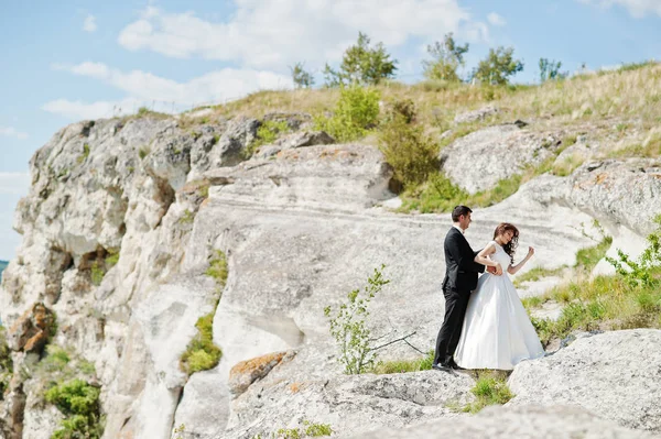 Свадебная пара на захватывающем пейзаже с камнем и озером . — стоковое фото