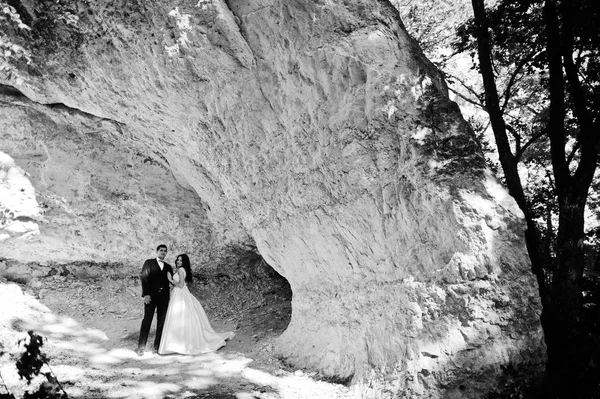 Wedding couple against cave at summer day. — Stock Photo, Image