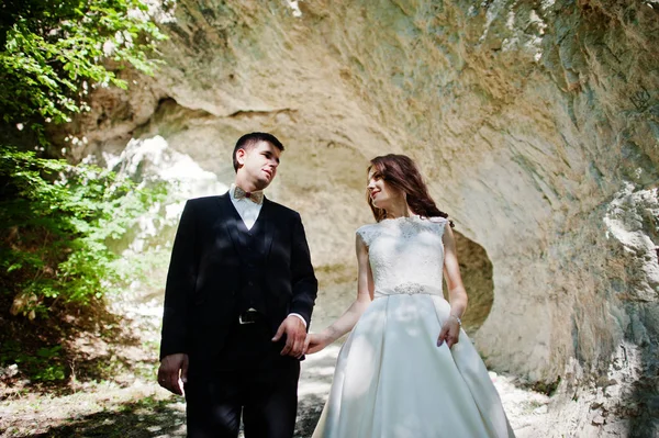 Wedding couple against cave at summer day. — Stock Photo, Image