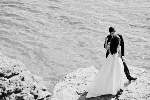 Hochzeitspaar in atemberaubender Landschaft mit Fels und See. — Stockfoto