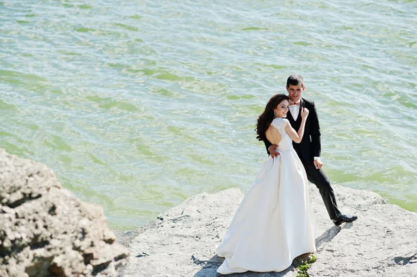 Wedding couple at breathtaking landscape with rock and lake. — Stock Photo, Image