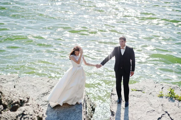 Wedding couple at breathtaking landscape with rock and lake.