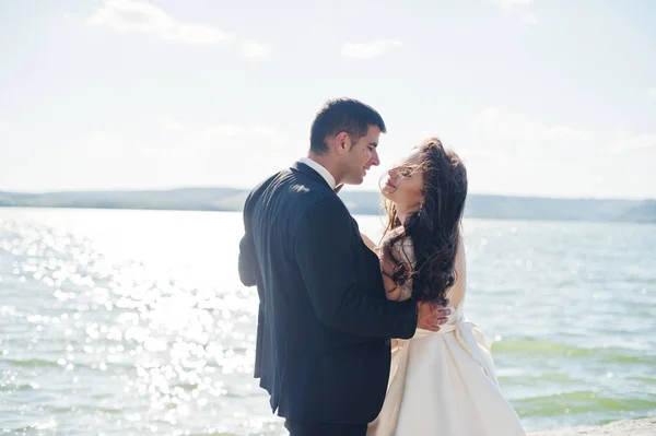 Hochzeitspaar in atemberaubender Landschaft mit Fels und See. — Stockfoto