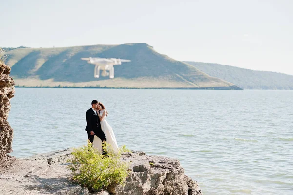 Wedding couple at breathtaking landscape with rock and lake.