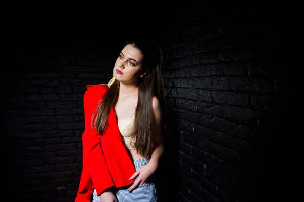 Stylowa Dziewczyna Brunetka na czerwonej kurtce przeciwko studio czarny cegła w — Zdjęcie stockowe