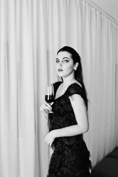Брюнетка дівчина у чорному фраку проведення келих вина знову — стокове фото