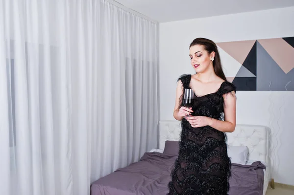 Brünettes Mädchen im schwarzen Abendkleid hält wieder ein Glas Wein — Stockfoto