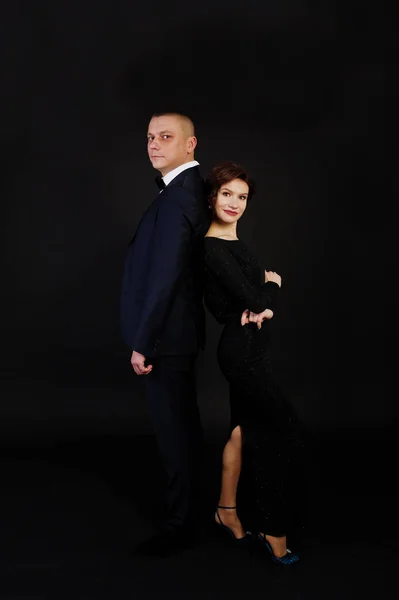 Femme élégante en robe de soirée noire avec l'homme en costume posé sur — Photo