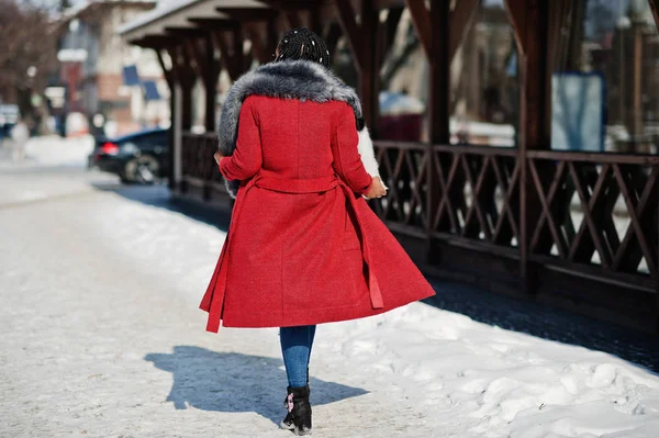 Back of walking rich african american girl in red coat and fur o