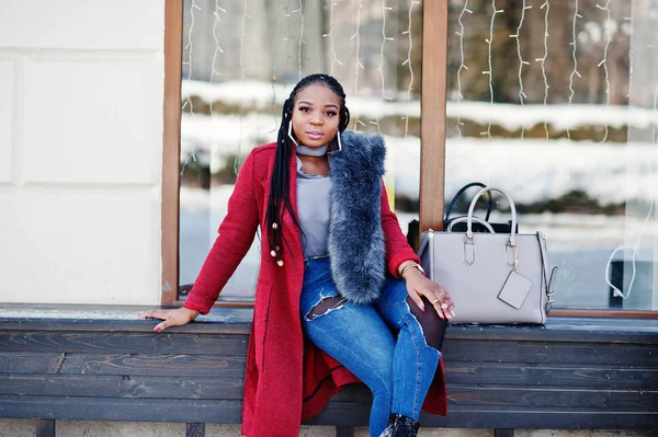 Rica chica afroamericana en abrigo rojo y piel sentada en el banco — Foto de Stock