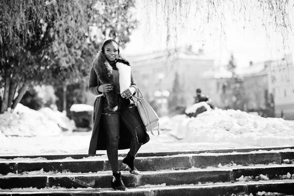 Рич африканская девушка в красном пальто и мехе с сумочкой в руках — стоковое фото