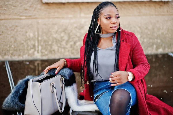 Rica chica afroamericana en abrigo rojo y piel sentada con la mano — Foto de Stock