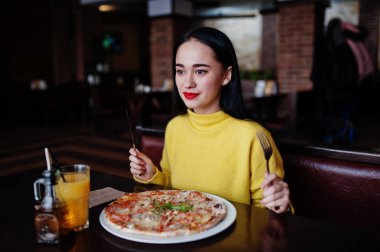 Esmer kız sarı kazaklı pizza restoranında yemek
