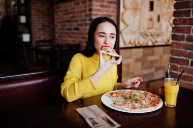 Esmer kız sarı kazaklı pizza restoranında yemek