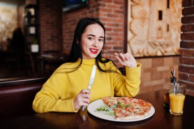 Esmer kız sarı kazaklı pizza restoranında yemek