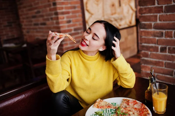 Zabawna Dziewczyna Brunetka w żółty sweterek jedzenie pizza w restauracji — Zdjęcie stockowe