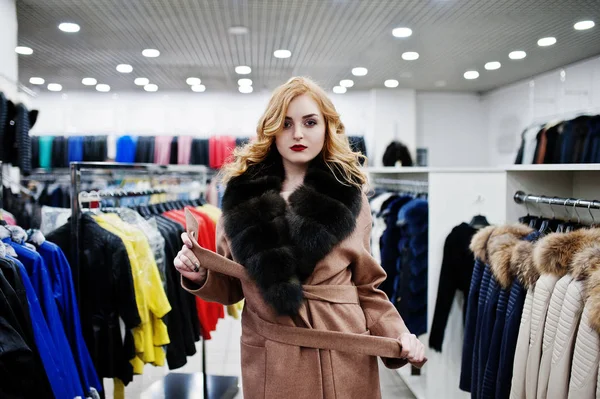 Elegance blonde girl in fur coat at the store of fur coats and l