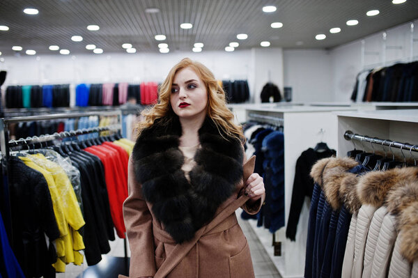 Elegance blonde girl in fur coat at the store of fur coats and l