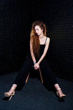 Kız sandalye siyah geri tuğla üzerinde dreads ile stüdyo çekimleri