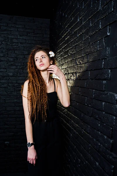 Studio shoot van meisje in zwart met dreadlocks op baksteen achtergrond. — Stockfoto
