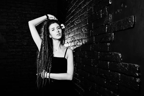 Studio shoot van meisje in zwart met dreadlocks op baksteen achtergrond. — Stockfoto