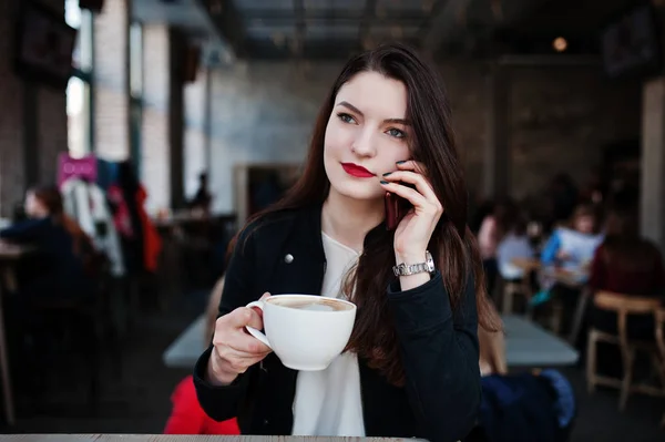 Brunette girl sitting on cafe with cup of cappuccino and speakin — Stock Photo, Image
