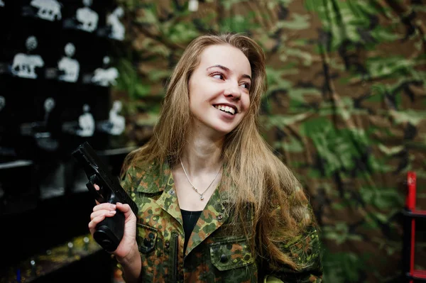 Военная девушка в камуфляжной форме с пистолетом под рукой — стоковое фото