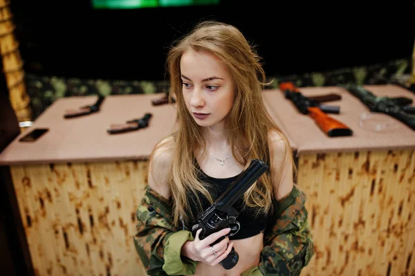Военная девушка в камуфляжной форме с пистолетом под рукой — стоковое фото