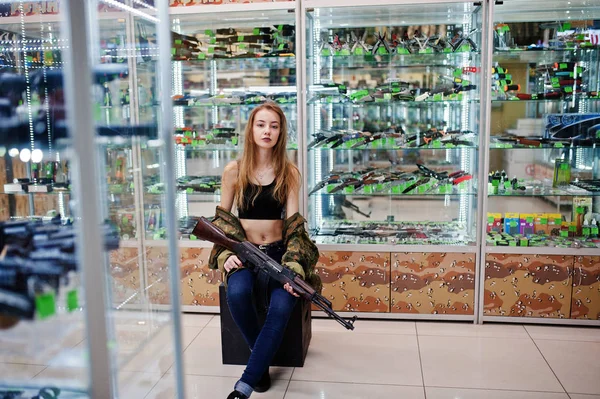 Girl with machine gun at hands on army store shop. — Stock Photo, Image