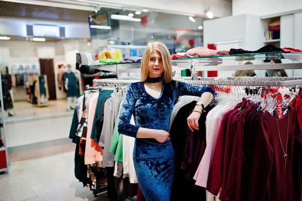 Blondes Mädchen in blauem Kleid in der Boutique eines Bekleidungsgeschäfts. — Stockfoto