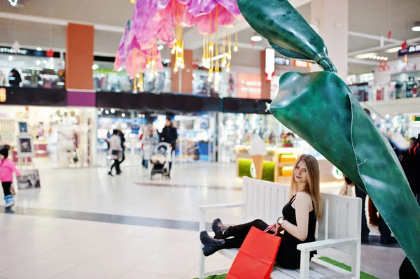 Meisje met boodschappentassen in het winkelcentrum zit op bankje. — Stockfoto