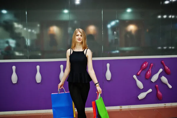 Dívka s nákupní tašky v obchoďáku proti bowling club zeď. — Stock fotografie