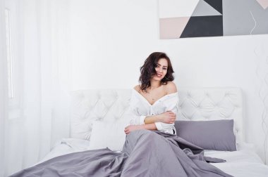 Beyaz bluz yatakta yatarken esmer kız portresi stüdyo.