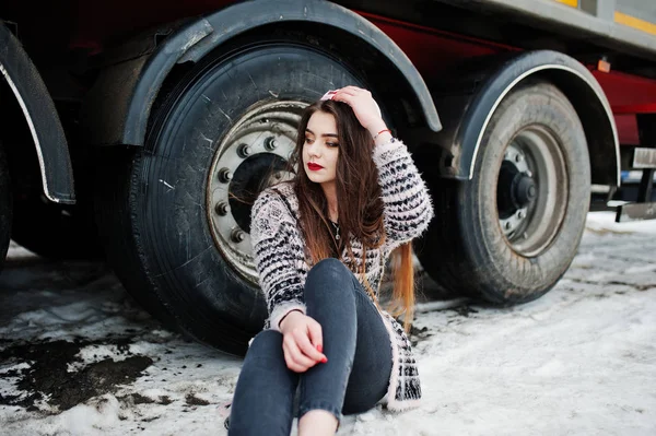 Brunette stylish casual girl in cap sitting against truck wheels — Stock Photo, Image