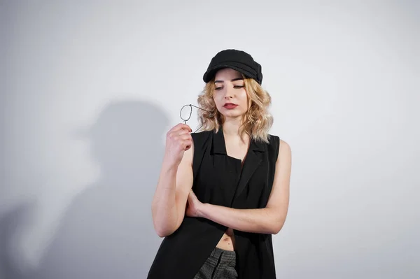 Studio portrait of blonde girl in black wear and cap against whi — Stock Photo, Image