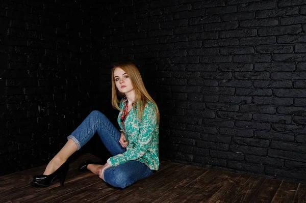 Elegante ragazza bionda in giacca e jeans contro muro nero mattone — Foto Stock