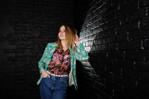 Стильна блондинка в куртці і джинсах проти цегляної чорної стіни — стокове фото