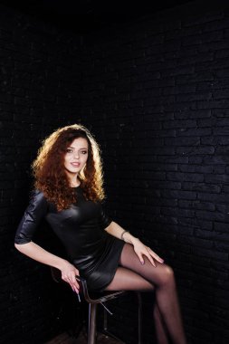 Esmer kıvırcık saçlı uzun bacaklı kız siyah deri elbise poz