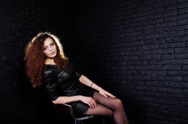 Esmer kıvırcık saçlı uzun bacaklı kız siyah deri elbise poz