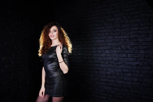 Brunette gekrulde haired lange benen meisje in zwart leer jurk pose — Stockfoto