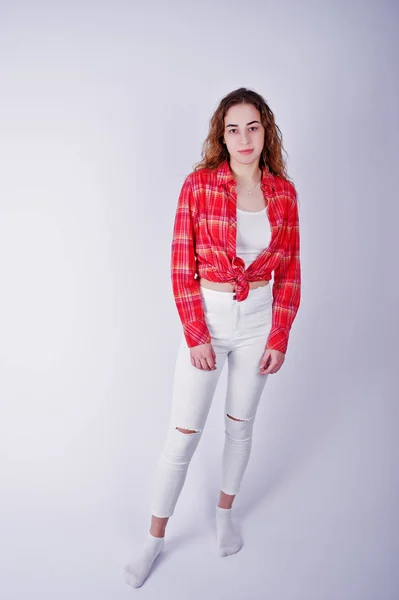 Jong meisje in de rode ingecheckte shirt en witte broek tegen witte ba — Stockfoto