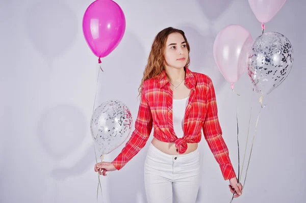 Young girl in red checked shirt and white pants with balloons ag